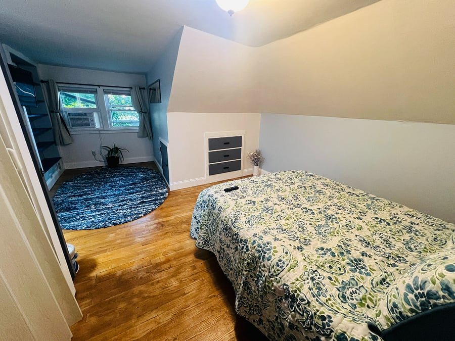 "Shoreview" Bedroom 2nd floor. Double bed, nightstand, built-in drawers and shelving, closet, desk, TV, AC unit, area rug on hardwood floor