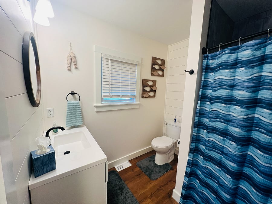Newly renovated, spacious, bathroom with vanity with ample storage, toilet,  large tub with shower, linen closet, hardwood flooring.