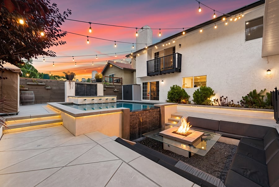 Resort-Style Pool & Fire Pit Lounge
Your private oasis! Take a dip in the custom illuminated pool featuring soothing water fountain jets, then gather around the sunken fire pit on comfortable wrap-around seating as string lights twinkle overhead.