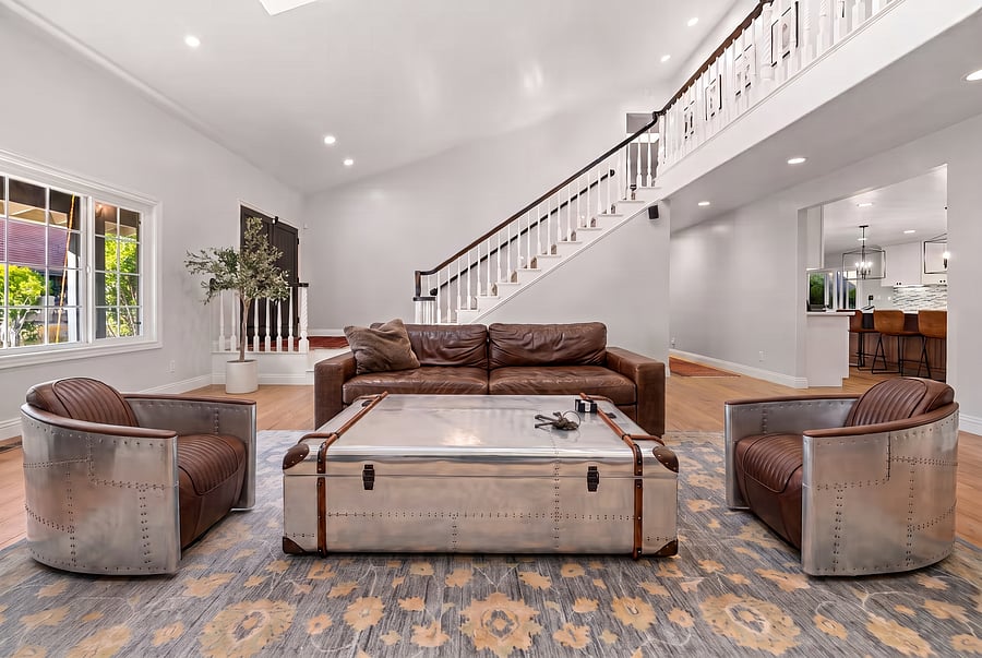 Living Room with Staircase & Luxury Seating
Chic & comfortable! This vaulted 1st-level living room features bright skylights, a sweeping staircase, and eye-catching aviator-style furniture from the RH Aviation Collection.