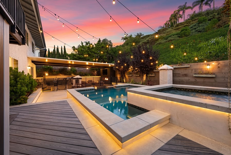 Illuminated Backyard Pool & Spa
Spa night is every night! This captivating twilight view shows off the glowing pool, the raised custom spa, the fire pit area, and the covered patio, all nestled below the hill under a brilliant, string-lit sky.