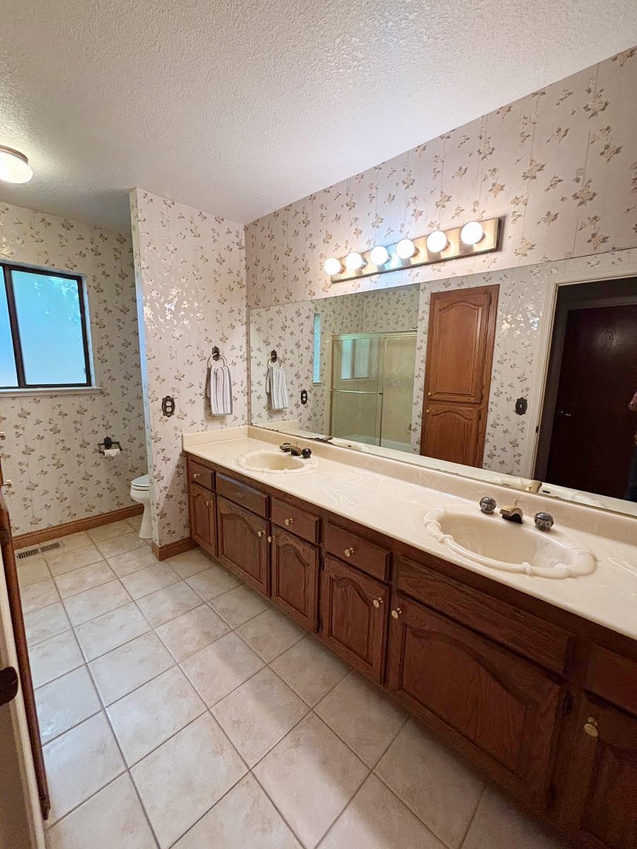 Hall bathroom with dual sinks and shower over the tub