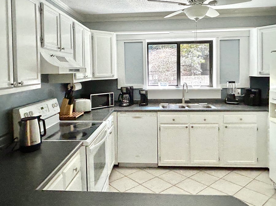 Kitchen with toaster, stove, microwave, drip coffee maker, K coffee maker, blender, air-fryer, refrigerator, pantry.