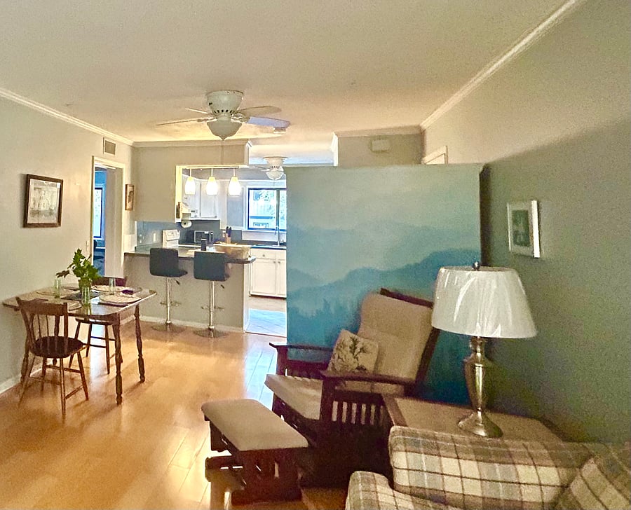 View from living room to kitchen. Back of coat closet with Blue Ridge Mountains scene. Breakfast bar with stools.