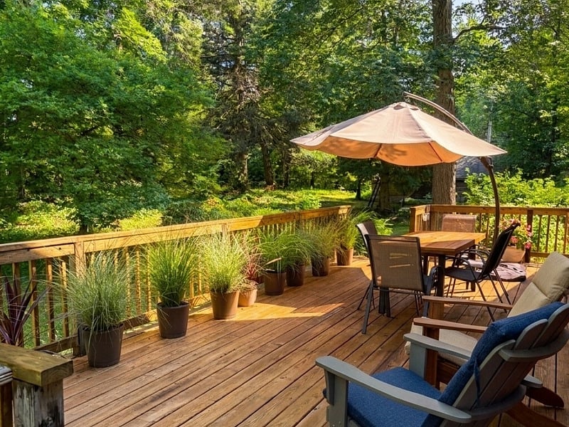 Outdoor deck with large umbrella, dining table & chairs, and lounge chairs.
