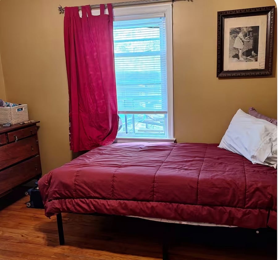 The bedroom has a single bed under the window, a dresser, a closet, and a desk. A simple and practical space for a single traveler. A ceiling fan provides air circulation and white noise for a cool, peaceful night.