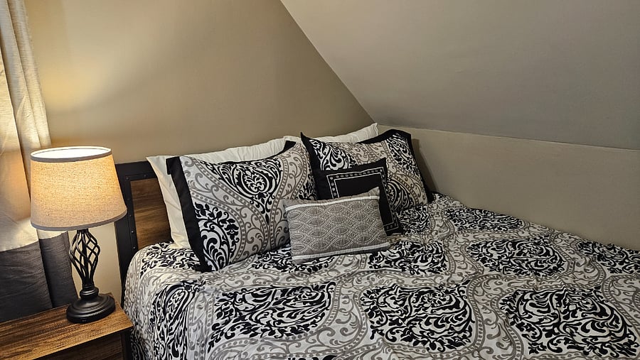 Cozy upstairs south bedroom with a queen bed tucked beneath the original roofline.