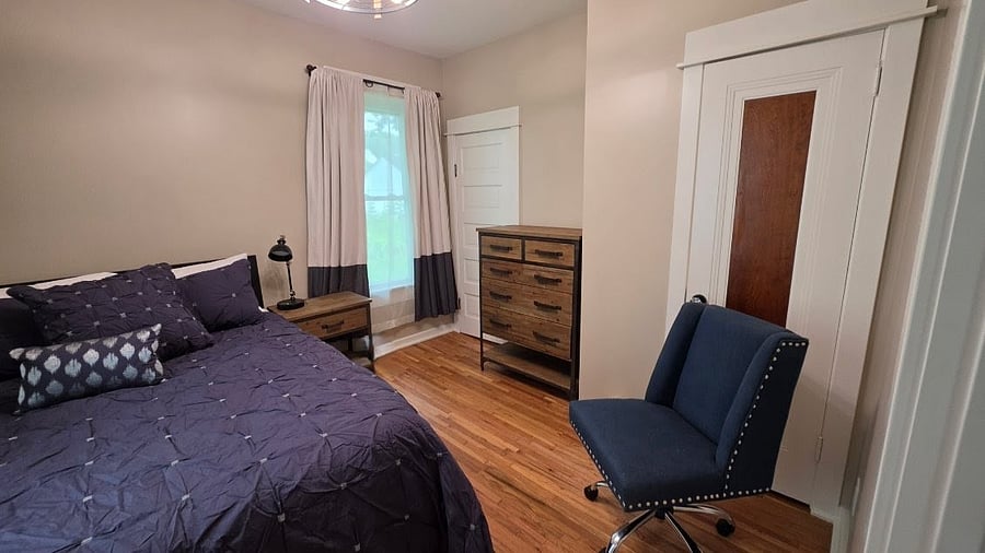 Main-floor bedroom with dresser and seating and easy access to the full bathroom.