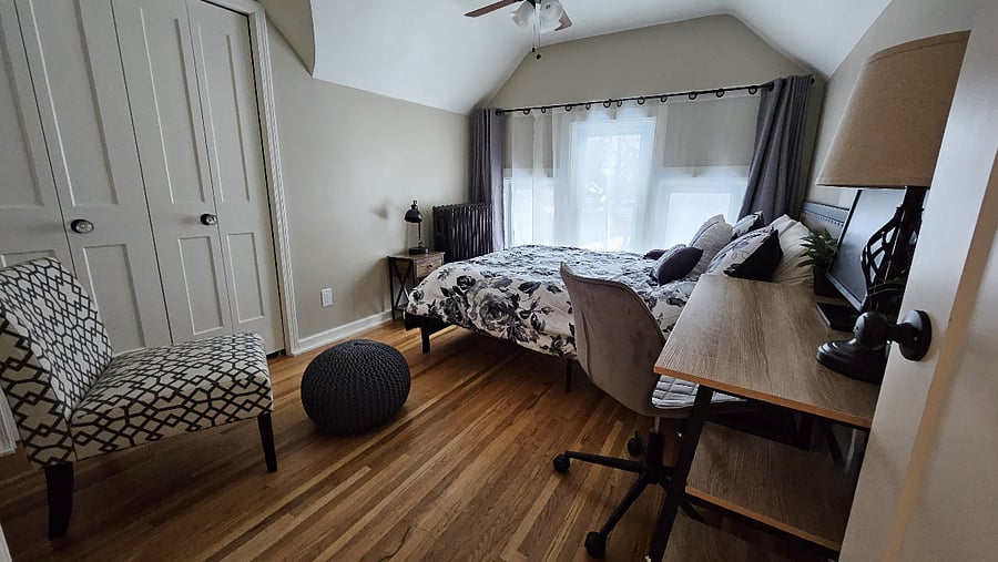 Queen bedroom with dedicated workspace and seating for extended stays.