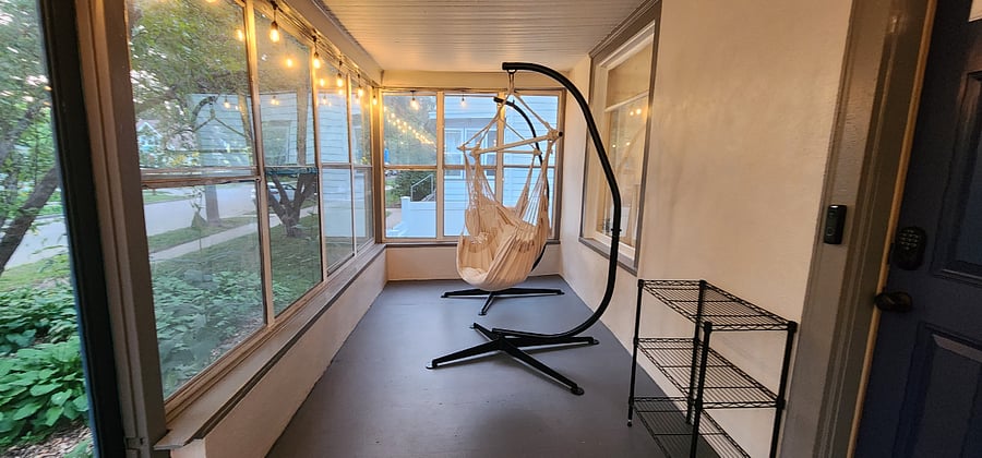 Relax on the screened front porch with hanging hammock chairs and string lights.