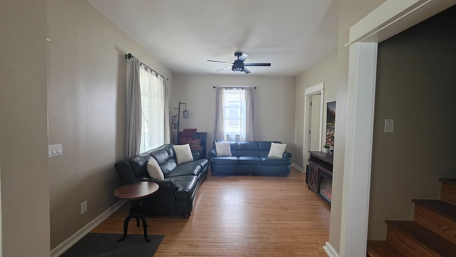 Living room with multiple seating areas, hardwood floors, ceiling fan, and Samsung Frame TV.