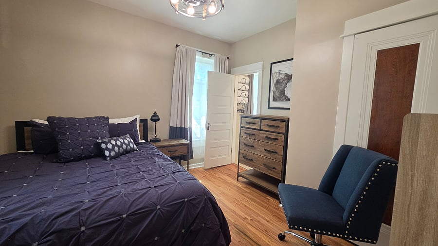 Main-floor, Main Bedroom, with queen bed and windows overlooking the fenced backyard; the homes full bathroom is conveniently located just outside the room.