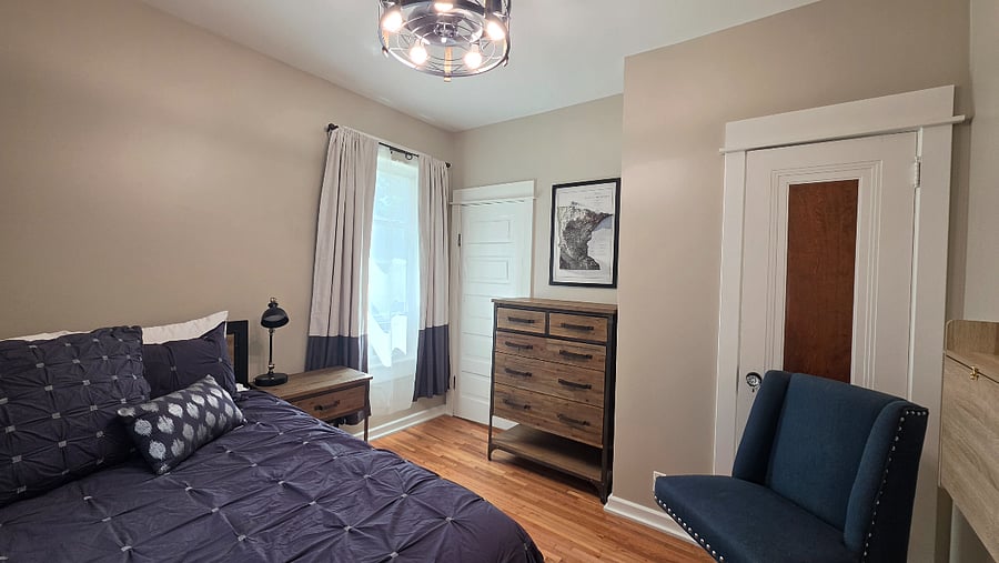 Main-floor bedroom with dresser and seating and easy access to the full bathroom.