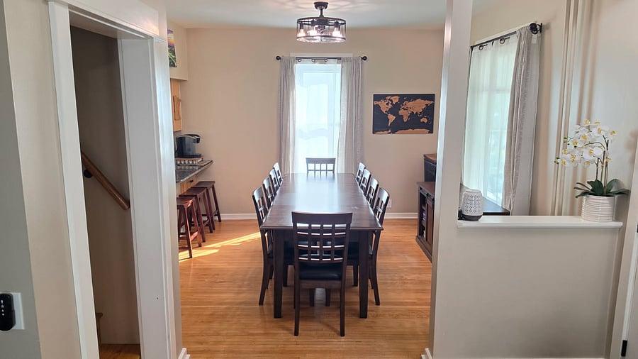 A wider view of the dining room with the table expanded for 10. The nearby kitchen breakfast bar offers additional seating, while the open layout keeps dining and everyday living spaces connected.