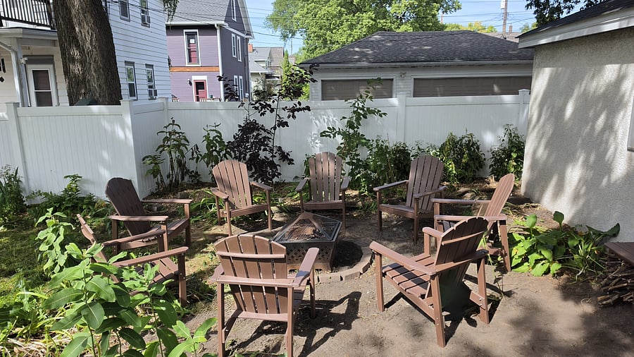 A separate backyard gathering area features Adirondack-style seating arranged around the fire pit, offering another place to relax and spend time together outdoors.