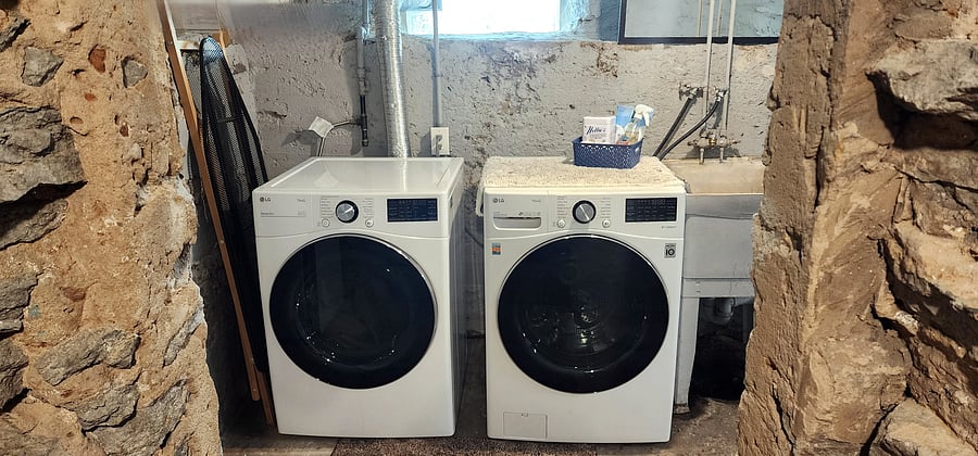An in-home, full-size LG washer and dryer make it easy to keep up with laundry during longer stays. The machines are located in the home's unfinished basement, with a utility sink nearby.