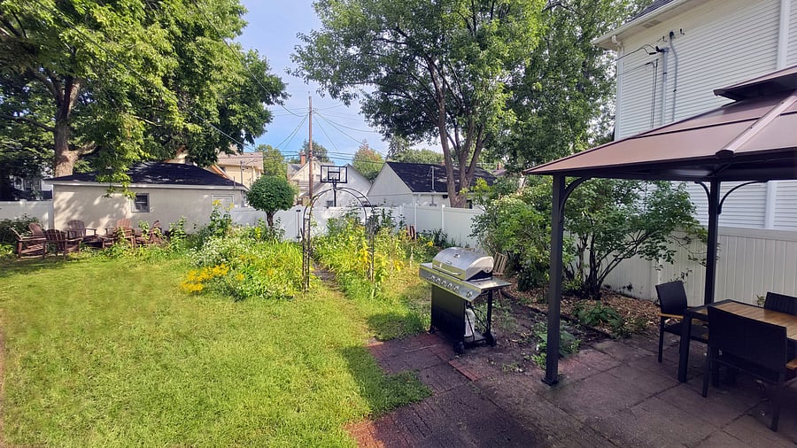 A private fenced backyard with plenty of lawn to enjoy, established gardens and mature trees, plus a full-size gas grill and covered outdoor dining area just steps from the house.