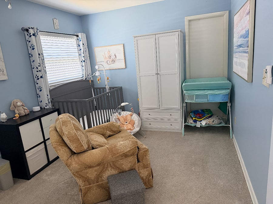 Nursery area in primary bedroom with full size crib, changing table, and rocker