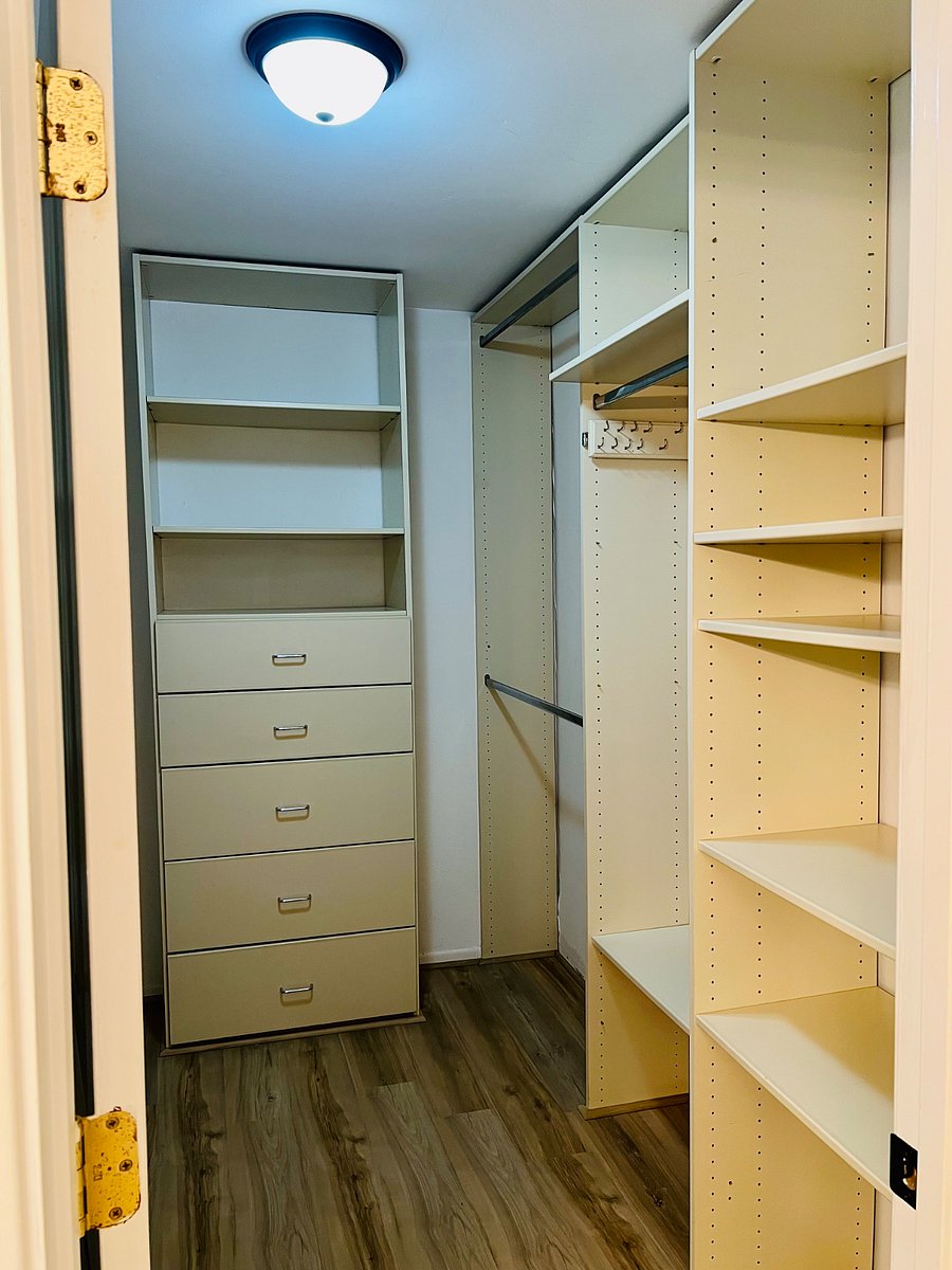 Primary bedroom walk-in closet with lots of shelves and poles for hanging items