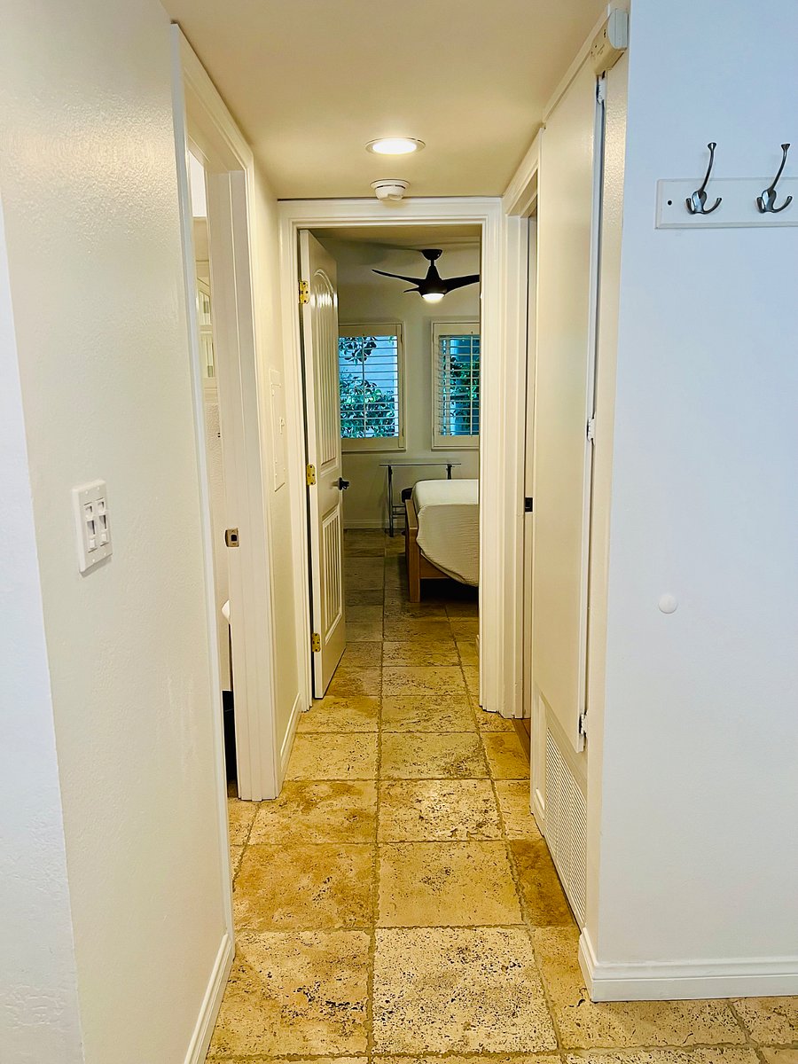 View of hallway from foyer into primary bedroom. On the left you'll see the guest bathroom and on the right is the linen closet and utility closet with iron/board, washer/dryer and vacuum