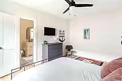 Bedroom 3 features a comfortable bed with soft linens, room-darkening curtains, a dresser, and a wall-mounted smart TV. Clean, cozy, and simple for a restful stay.
