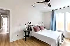 Bedroom 3 features a comfortable bed with soft linens, room-darkening curtains, a dresser, and a wall-mounted smart TV. Clean, cozy, and simple for a restful stay.