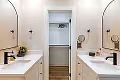 Spotlessly clean bathroom with double sinks, a glass-enclosed shower, and fresh towels provided. Basic toiletries are included for an easy, comfortable stay.