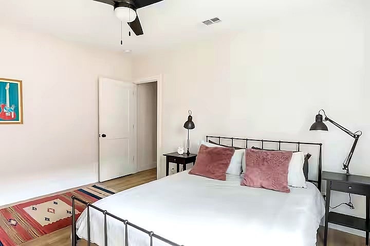 Bedroom 3 features a comfortable bed with soft linens, room-darkening curtains, a dresser, and a wall-mounted smart TV. Clean, cozy, and simple for a restful stay.
