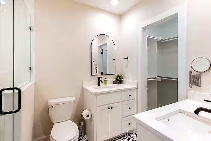 Spotlessly clean bathroom with double sinks, a glass-enclosed shower, and fresh towels provided. Basic toiletries are included for an easy, comfortable stay.