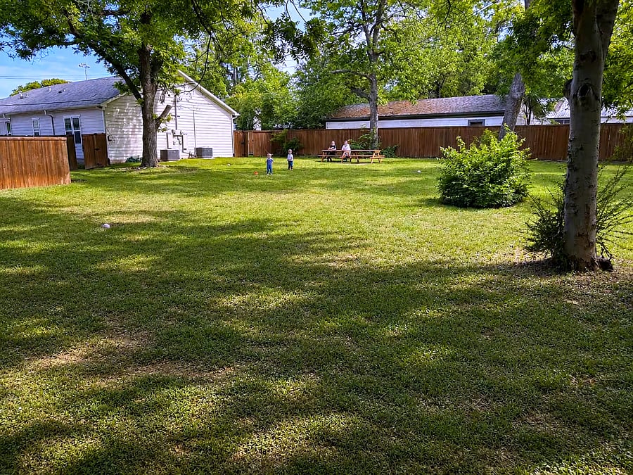 Spacious, fully fenced yard with plenty of room to relax, dine, and let kids or pets play under the shade of mature trees.