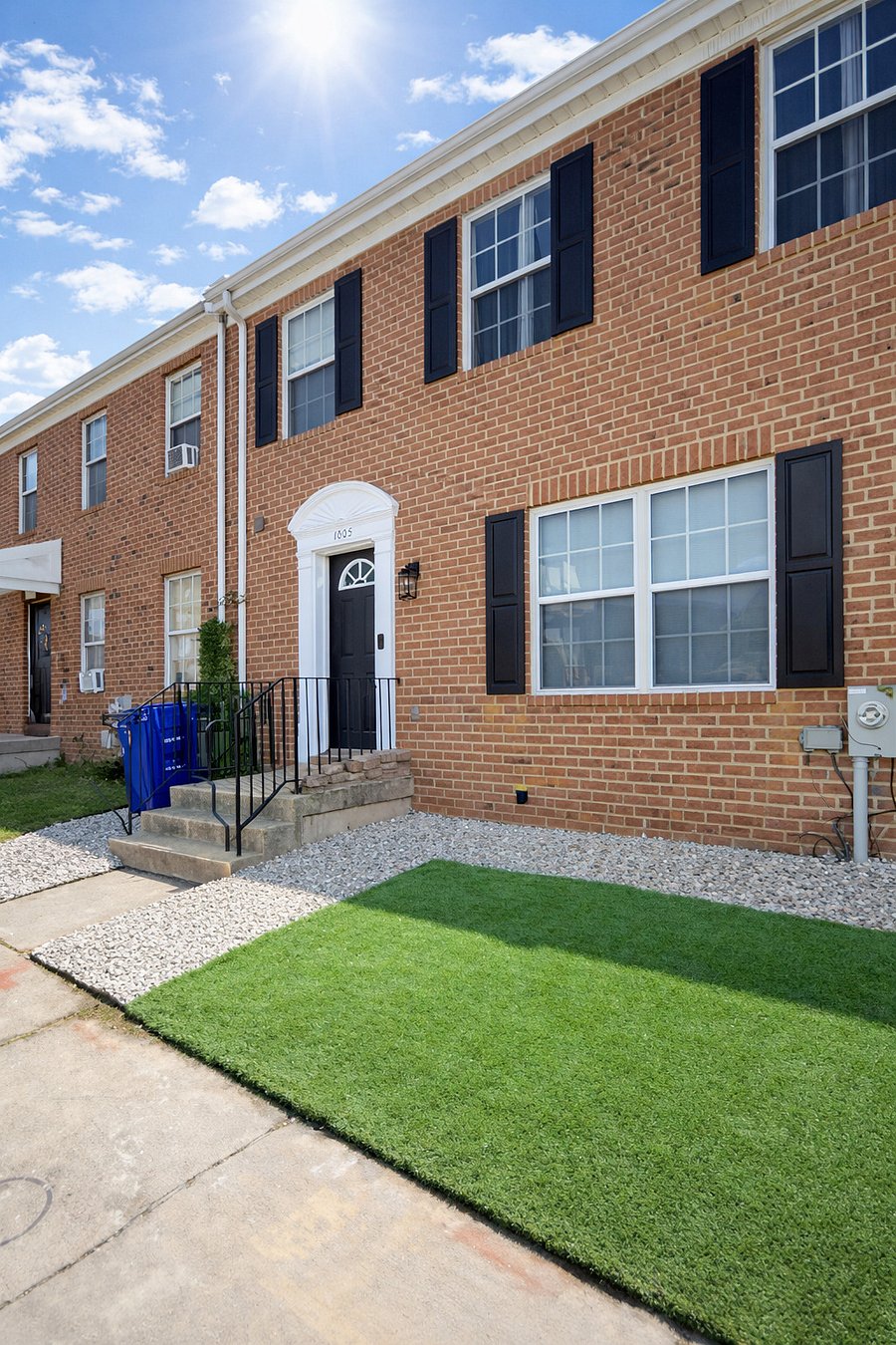 Brick rowhouse, black shutters. Low maintenance front yard