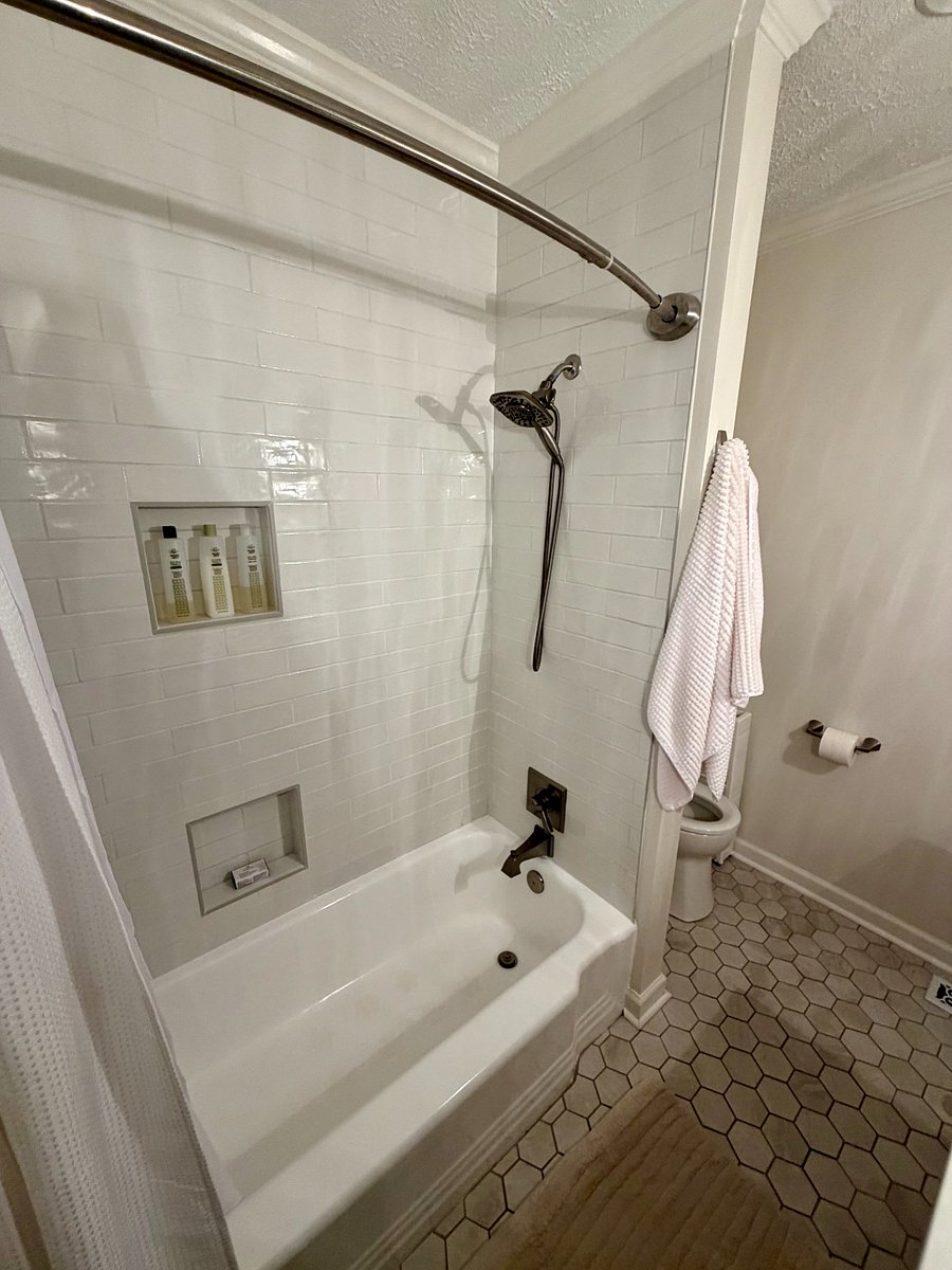 Primary Bathroom: Tub/shower combination with handheld showerhead and built-in shower niches.