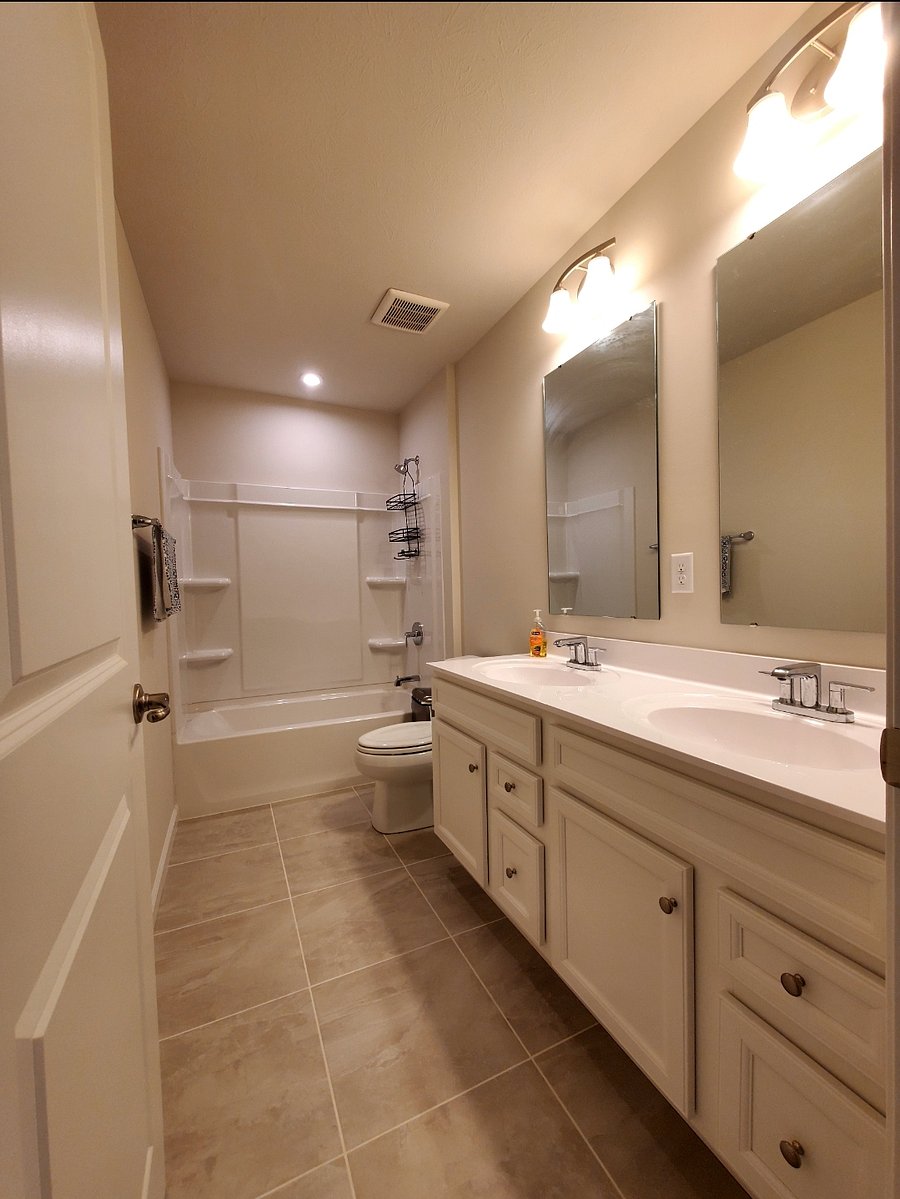 Private bathroom with tub and double sink vanity.
