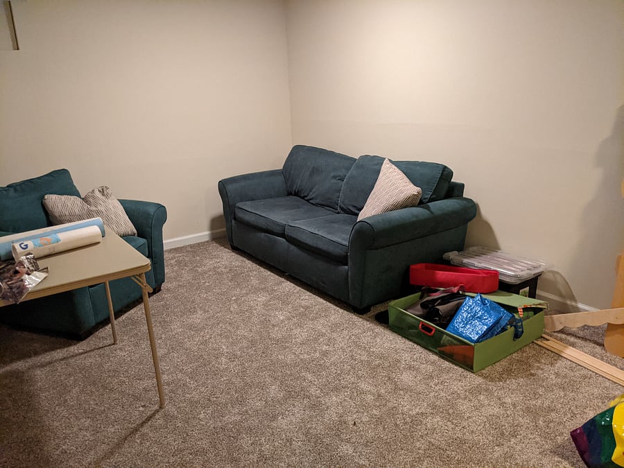 Basement living room includes a sleeper sofa, desk, and TV.