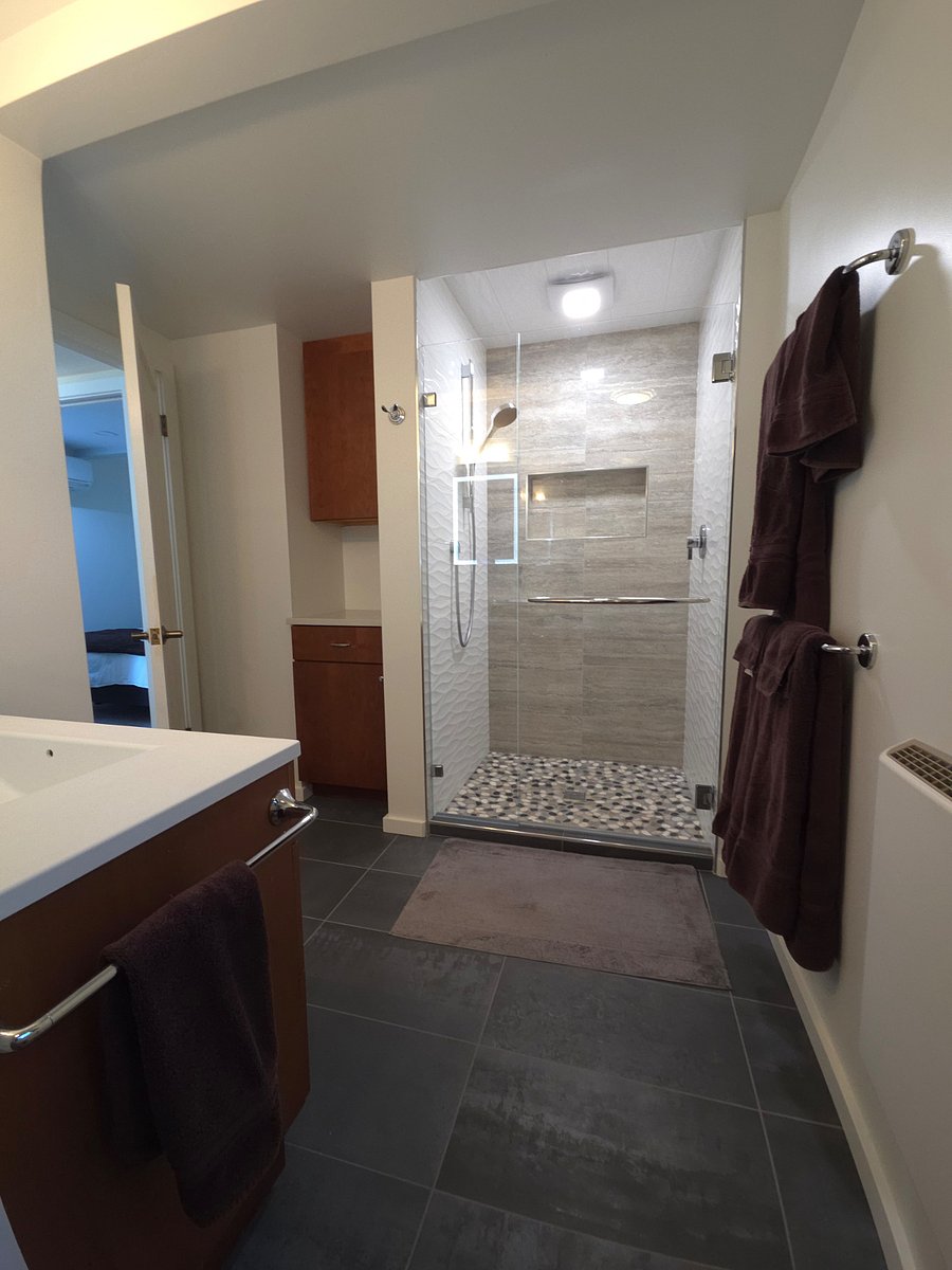 Earth-themed bathroom includes adjustable hand-held shower head and river rock floor.
