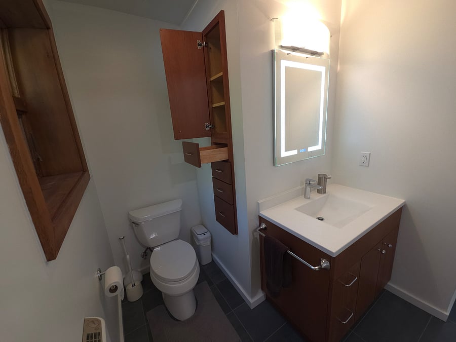 Pull out drawers in wall cabinet provide storage in addition to upper and lower cabinet next to shower.