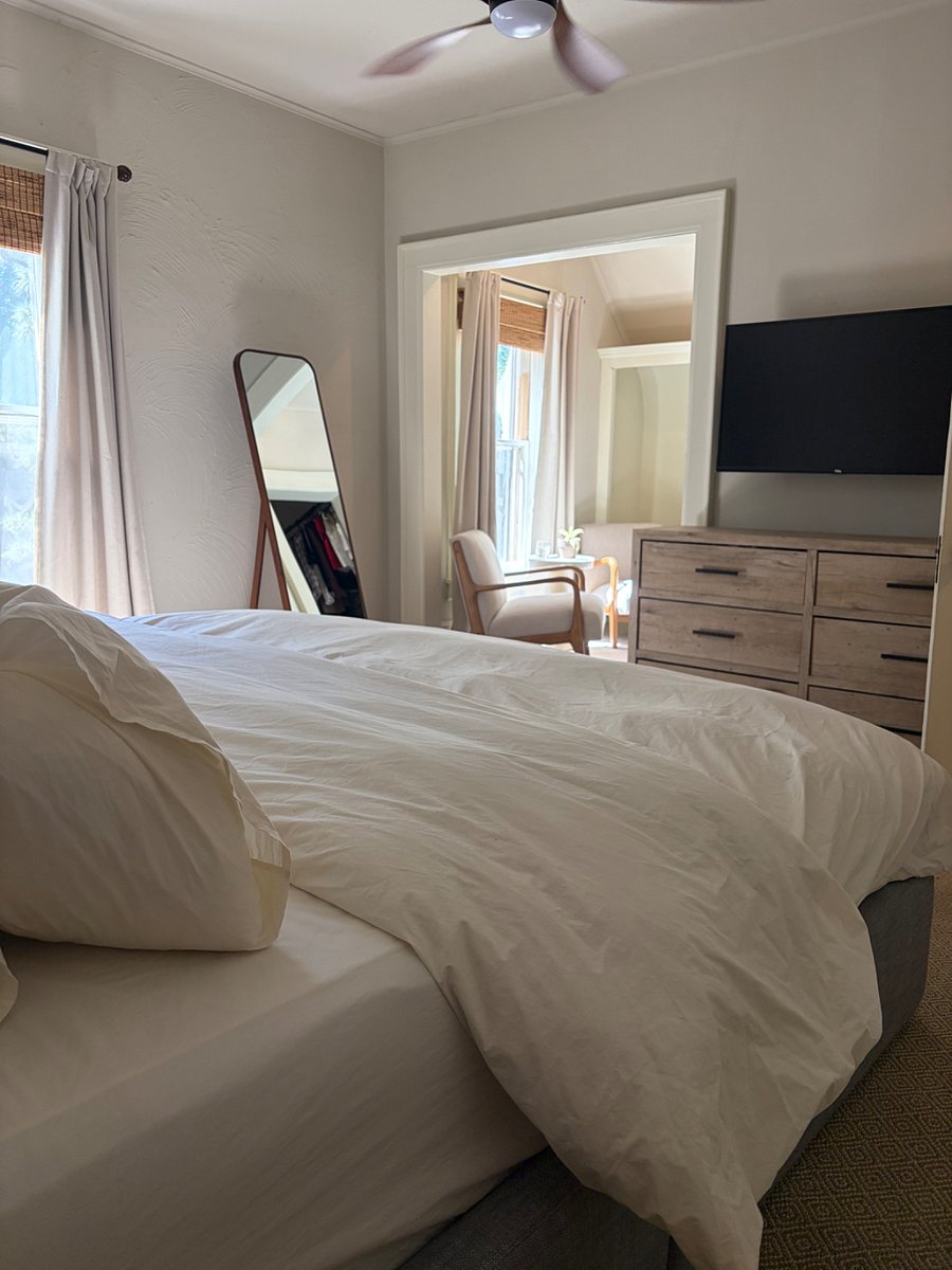 Primary bedroom, featuring a king bed, reading nook with two chairs, a smartTV, and walk-in closet