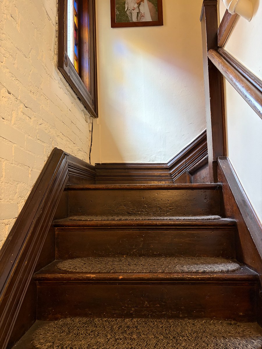 Stairs with original stained glass window leading to second floor