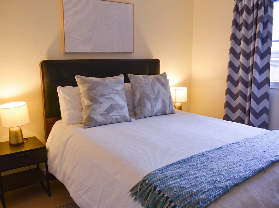 Third bedroom with full bed, hotel-quality linens, dual nightstands, and chevron blackout curtains ideal for shift workers needing daytime sleep. Closet included. Each bedroom has its own distinct style and smart TV.