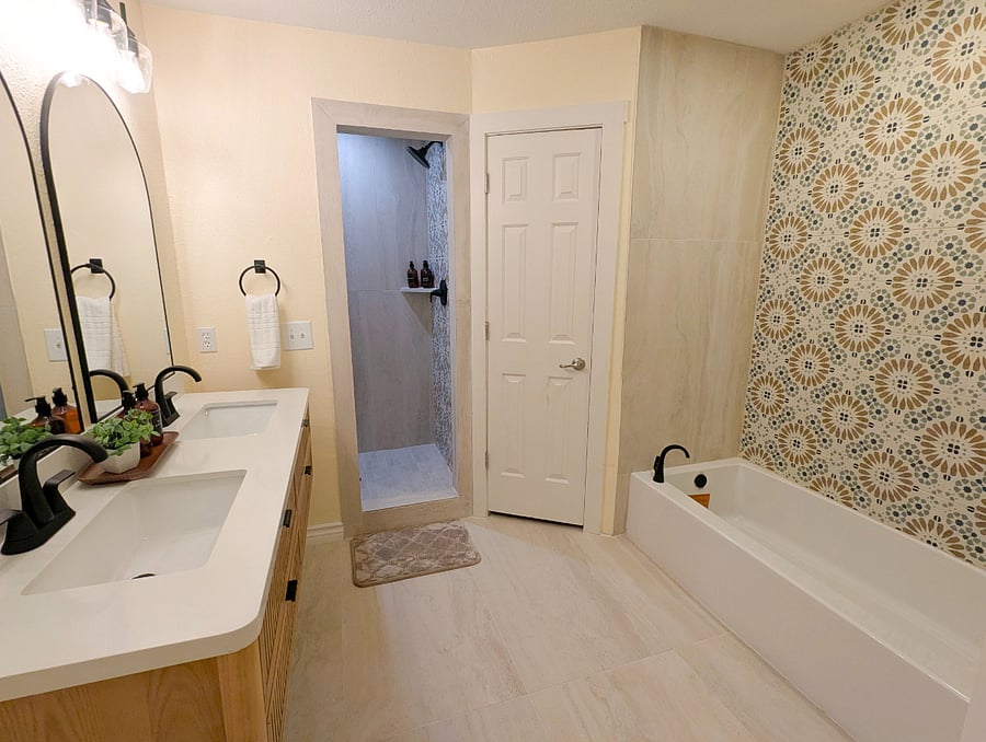 Fully renovated ensuite spa bathroom double vanity, soaking tub with hand-painted Moroccan mosaic tile wall, separate walk-in shower, black matte fixtures, and large format porcelain tile floors. Two private walk-in closets adjacent.