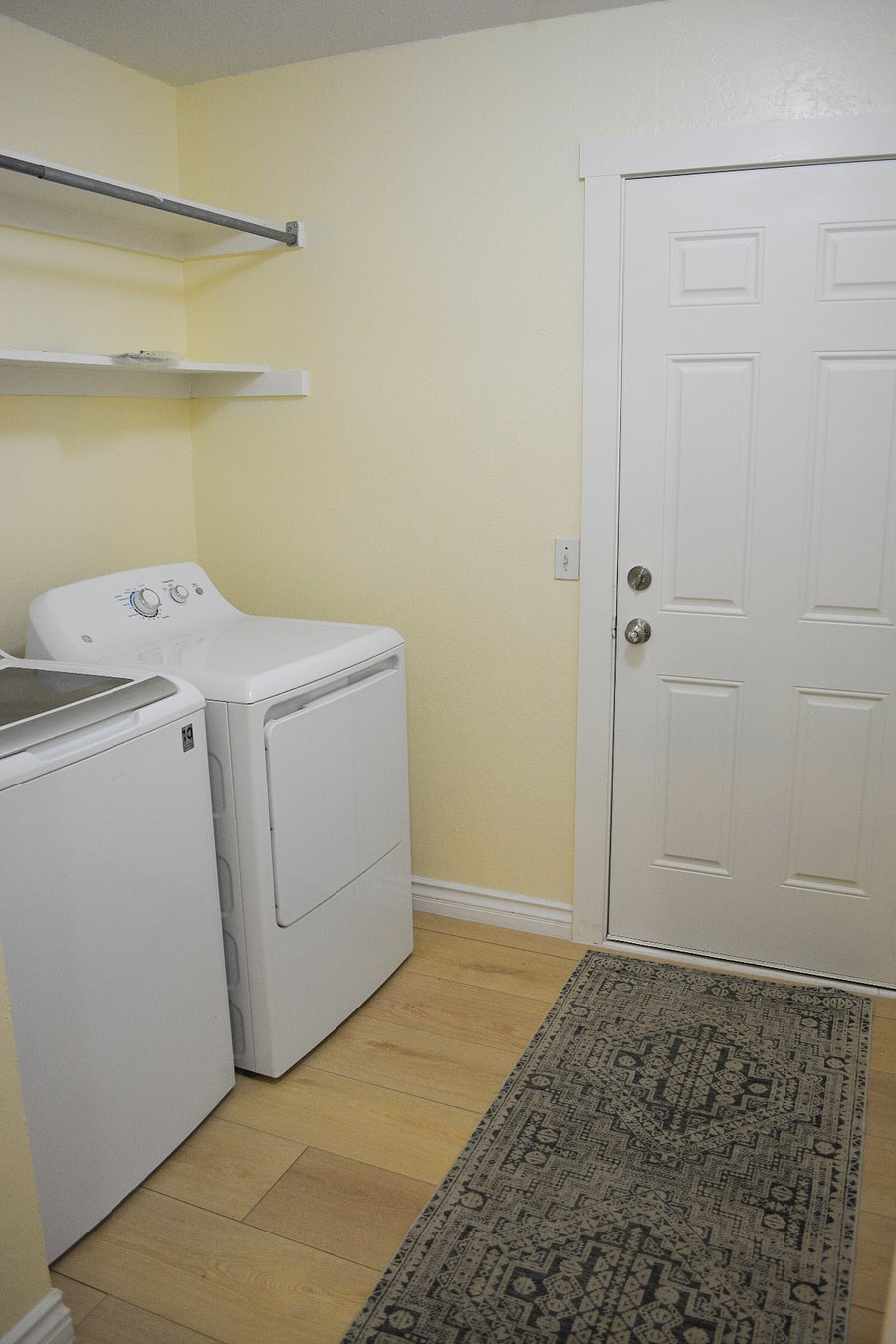 Dedicated laundry room with full-size GE top-load washer and dryer, built-in shelving, and garage access door. Detergent and dryer sheets provided. Pack light in-unit laundry makes extended stays effortless.