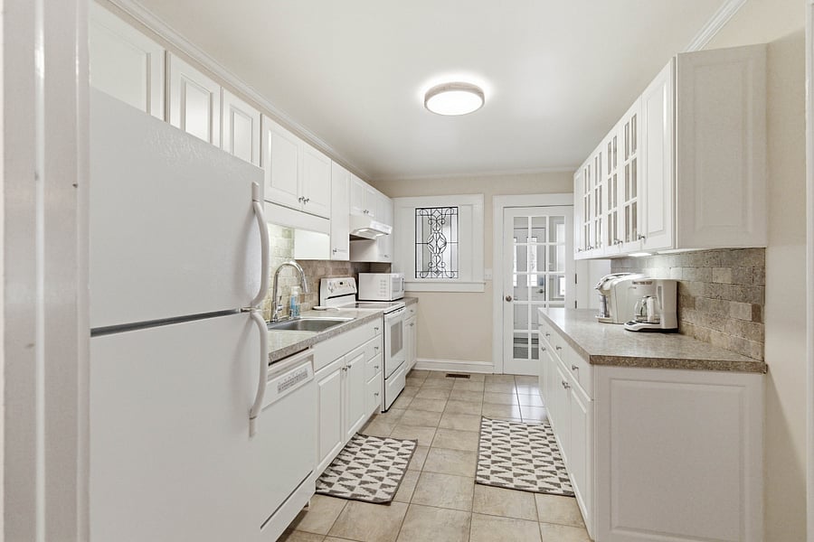 Fully stocked kitchen with coffee maker, keurig, microwave, crock pot, pots & pans, baking sheets, blender, stove, fridge, crockery.