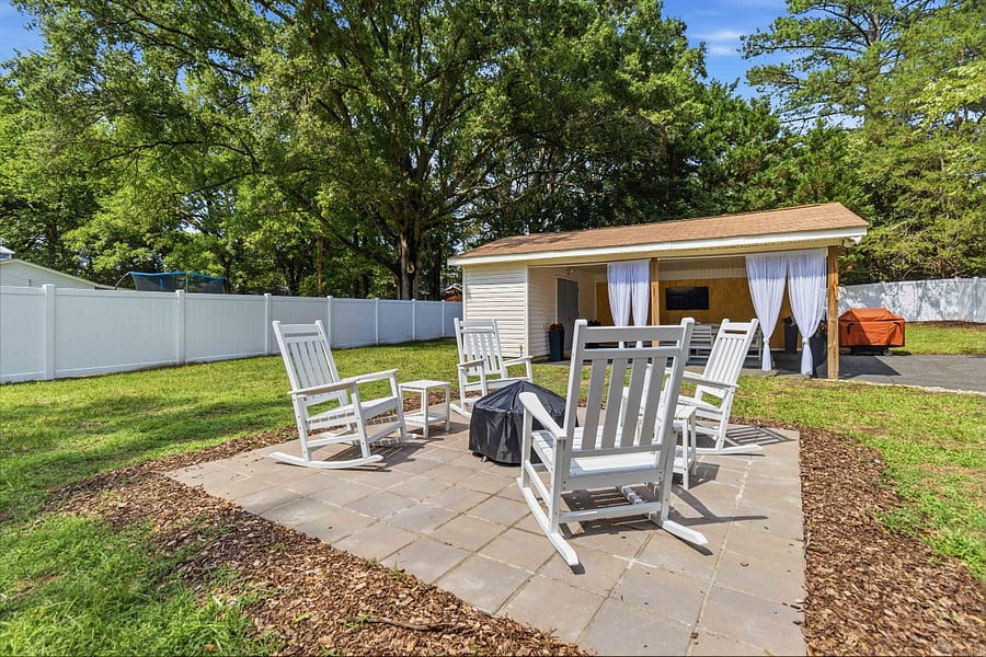 Wood fire pit with four rocking chairs and exterior lighting.