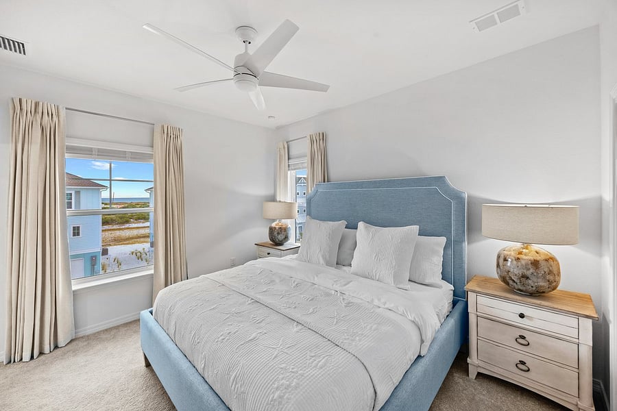Primary bedroom with 55" smart tv, dresser, closet, premium hybrid mattress, noise-maker, black out curtains, ceiling fan, and night stands. Peak-a-boo ocean views. 