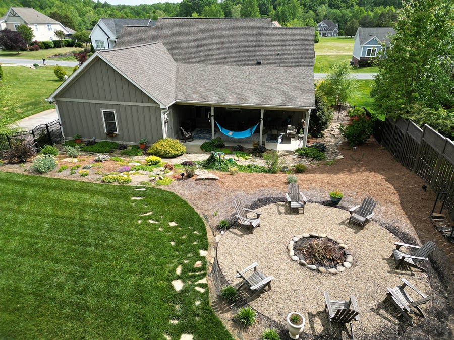 AERIAL PROPERTY VIEW: Showcasing the large, fully fenced-in private backyard, beautifully manicured landscaping, custom stone firepit lounge, and deep covered porch.