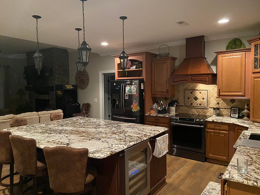 GOURMET KITCHEN: Massive granite kitchen island complete with a built-in wine fridge, offering a perfect, open view right into the central living room area.