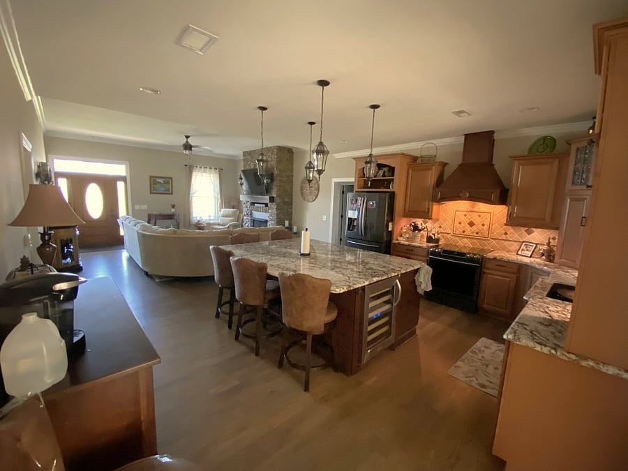 GOURMET KITCHEN: Massive granite kitchen island complete with a built-in wine fridge, offering an open view into the central living room area.
