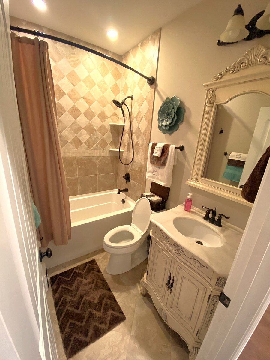 PRIVATE BATH: Located right in the center of your dedicated hallway wing. Fully equipped with a custom-tiled shower and tub combo, a single vanity, and modern lighting.