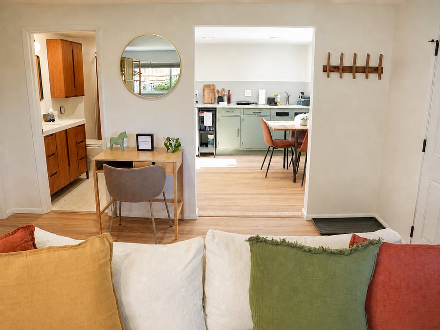 Open layout connecting living space to kitchenette and a laptop friendly workspace.