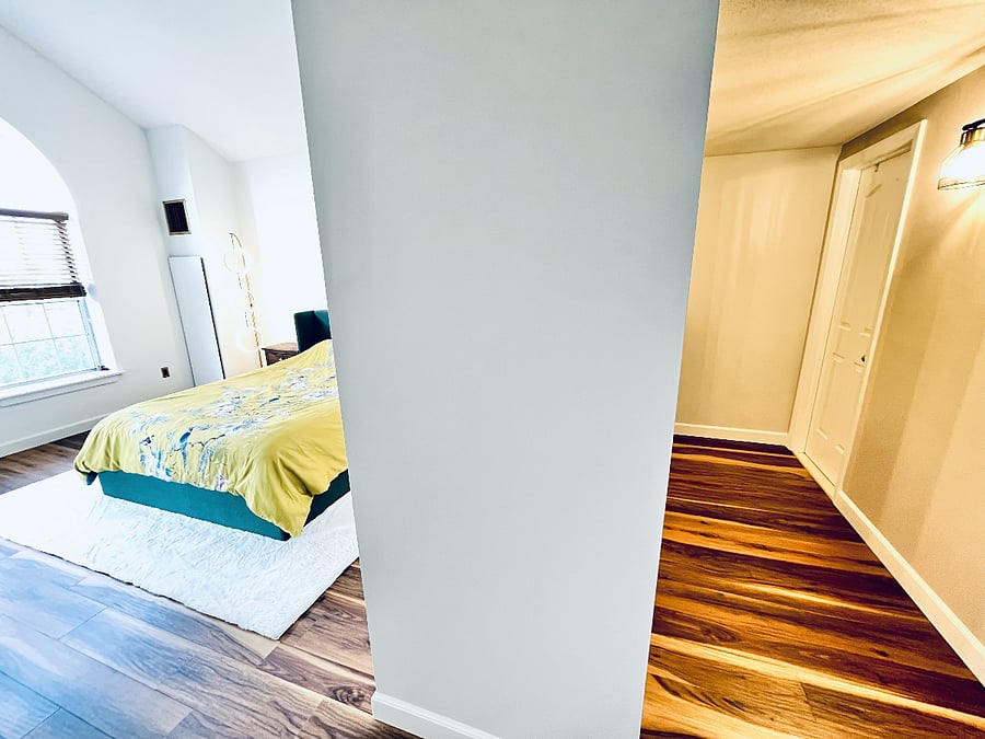 Private primary suite featuring a spacious sleeping area and a separate dressing corridor with generous closet storage.